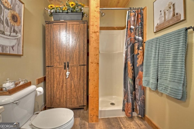 full bathroom with toilet, a stall shower, and wood finished floors