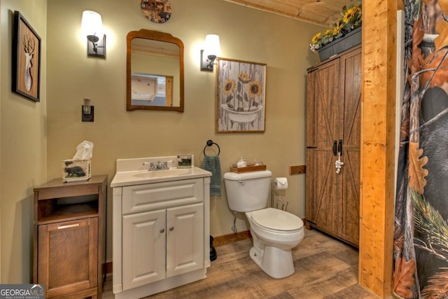 bathroom featuring toilet, baseboards, wood finished floors, and vanity