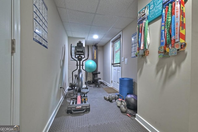 exercise area with a paneled ceiling and baseboards