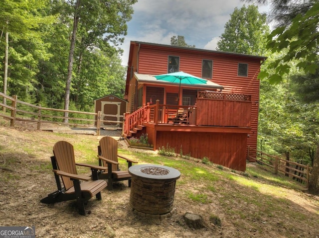 back of property featuring an outbuilding, log veneer siding, a fire pit, and a shed