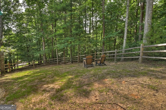 view of yard featuring a fenced backyard and a wooded view