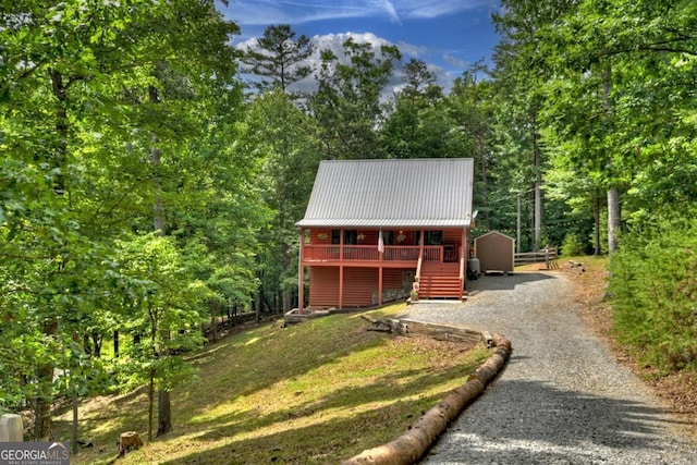 view of outdoor structure with an outbuilding, gravel driveway, and a wooded view