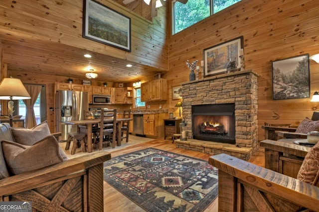 living room with a wealth of natural light, light wood-type flooring, wooden walls, and a ceiling fan