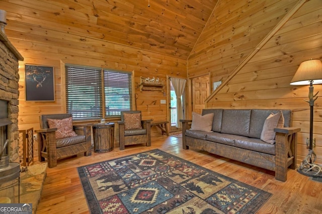 living room with hardwood / wood-style flooring, wooden walls, high vaulted ceiling, and a fireplace