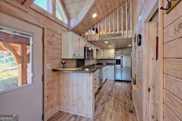 664 River Vista Dr, Dillard, GA 30537 - kitchen with appliances with stainless steel finishes, wood finished floors, vaulted ceiling, plenty of natural light, and wooden walls