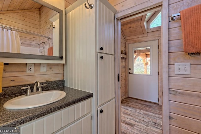 664 River Vista Dr, Dillard, GA 30537 - bathroom with wood walls, vanity, vaulted ceiling, wood finished floors, and curtained shower
