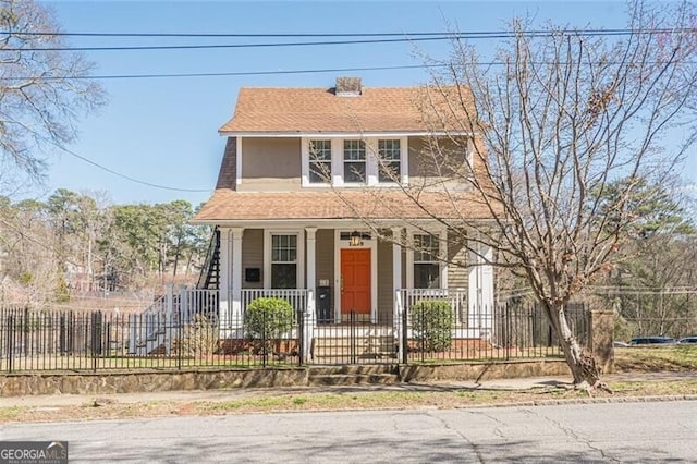 view of front of house featuring covered porch, roof with shingles, and a fenced front yard