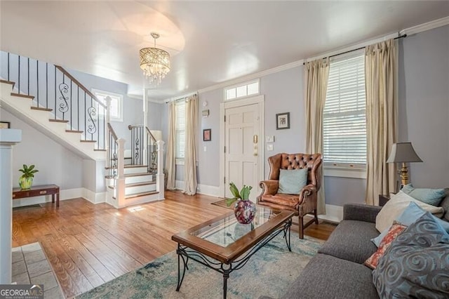 living room with stairway, ornamental molding, wood finished floors, a chandelier, and baseboards