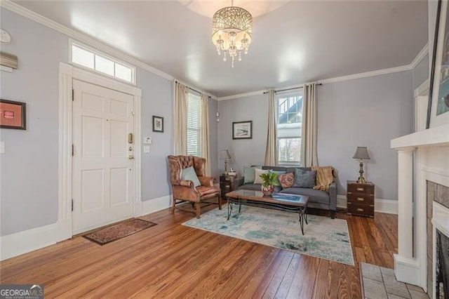 interior space featuring wood finished floors, ornamental molding, a tile fireplace, and baseboards