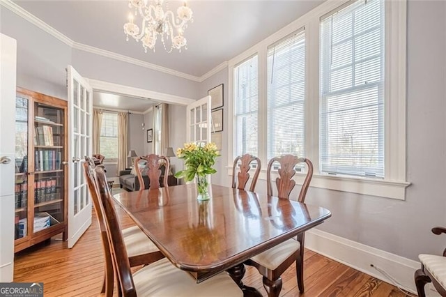 dining space featuring a notable chandelier, baseboards, wood finished floors, and crown molding