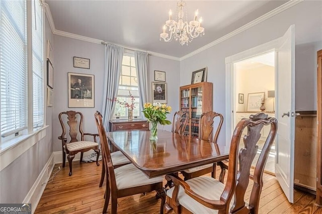 dining room with light wood-type flooring, baseboards, ornamental molding, and a notable chandelier