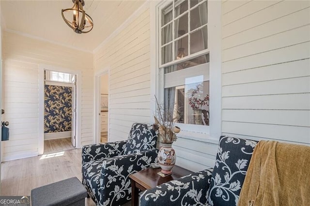 sitting room with baseboards, wood finished floors, and wooden walls