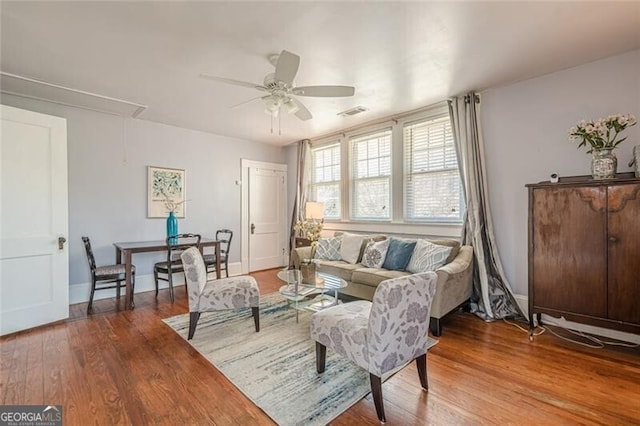 living room featuring attic access, ceiling fan, baseboards, and wood finished floors