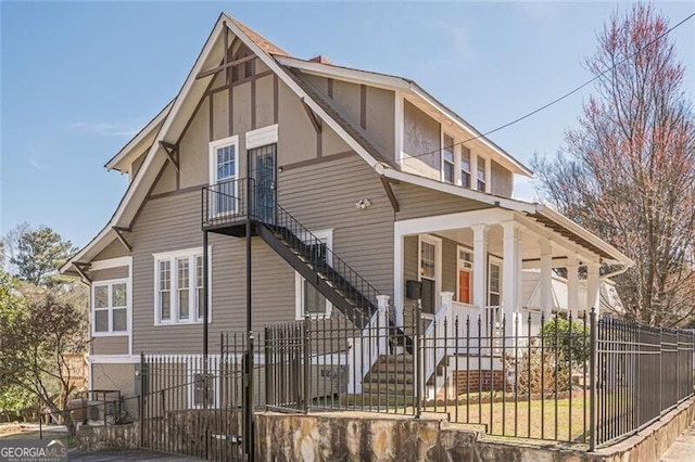 view of front of property with a fenced front yard, covered porch, and stairs