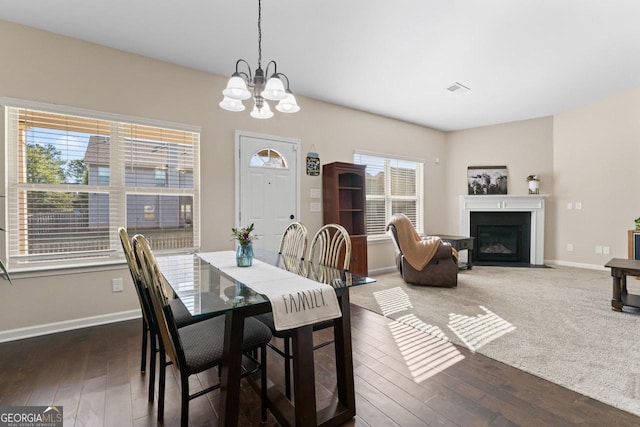 dining space with a fireplace with flush hearth, wood-type flooring, baseboards, and an inviting chandelier