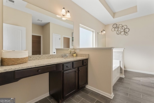 bathroom with baseboards, visible vents, a garden tub, wood tiled floor, and vanity