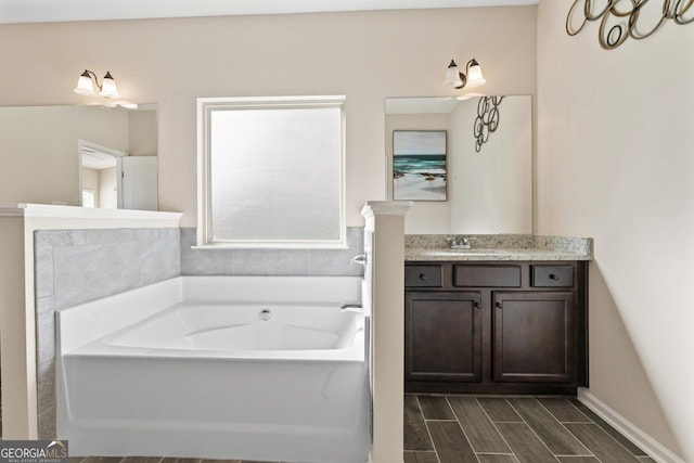 bathroom with wood tiled floor, a garden tub, and vanity