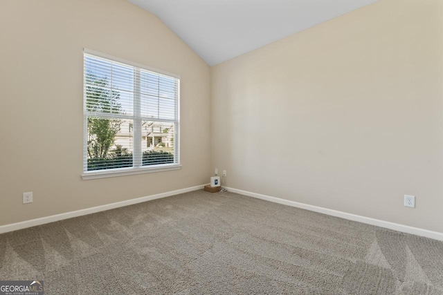 carpeted spare room with lofted ceiling and baseboards