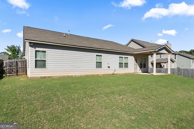 back of property featuring a fenced backyard, a yard, and roof with shingles