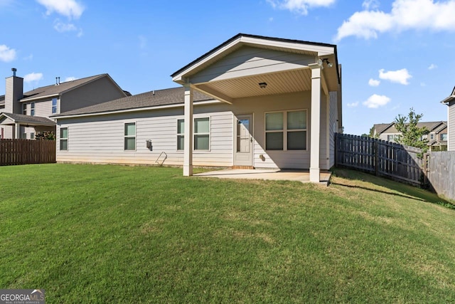 rear view of house with a patio area, a lawn, and a fenced backyard