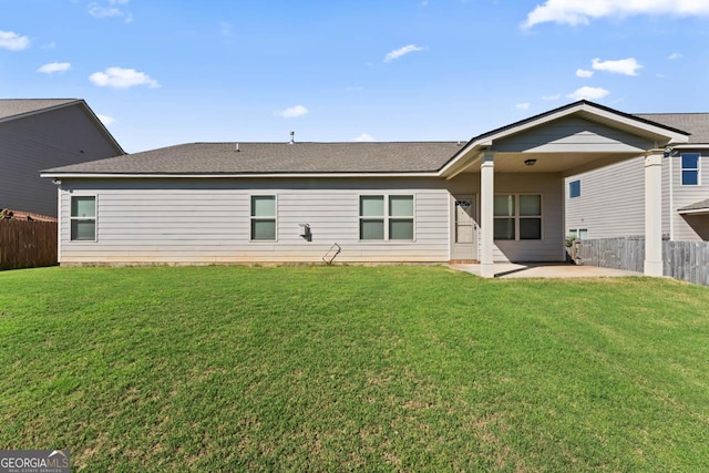 rear view of house with fence, a lawn, and a patio