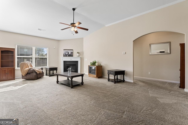 living room with arched walkways, a glass covered fireplace, ceiling fan, carpet, and vaulted ceiling