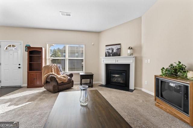 carpeted living room with a fireplace with flush hearth, visible vents, and baseboards