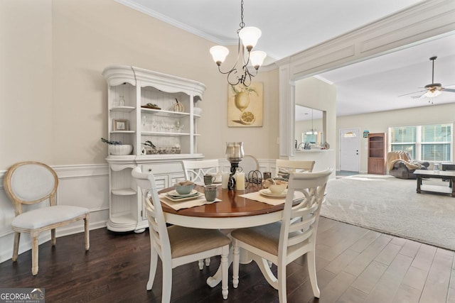 dining area featuring ceiling fan with notable chandelier, crown molding, and wood finished floors