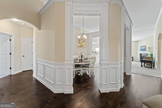 corridor featuring arched walkways, a decorative wall, and dark wood-type flooring