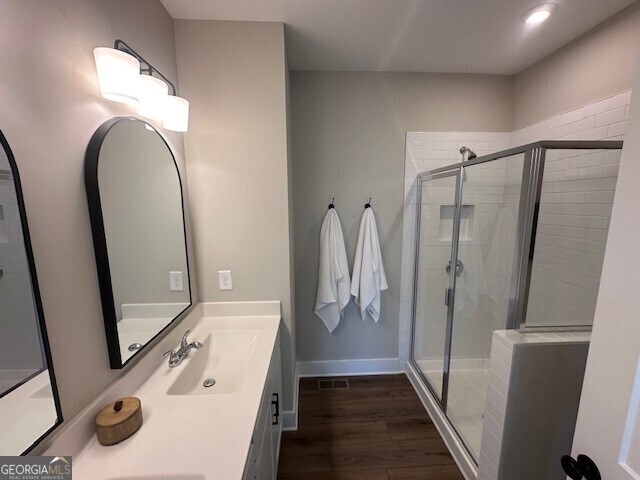 full bathroom featuring vanity, wood finished floors, visible vents, and a shower stall