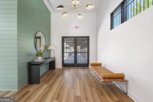 doorway featuring a towering ceiling, baseboards, wood finished floors, and french doors