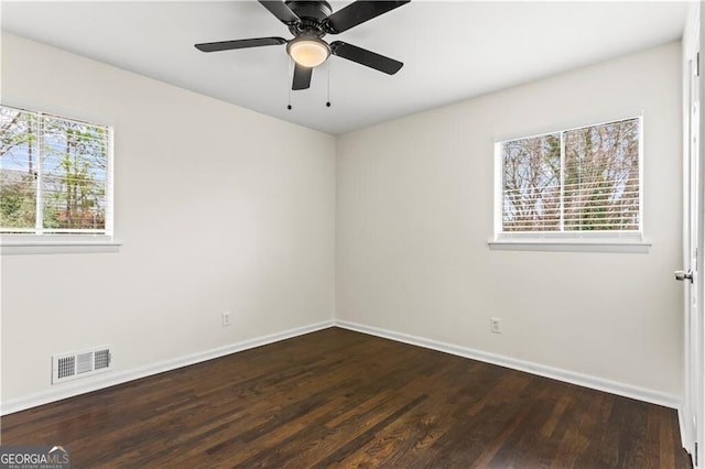 spare room featuring baseboards, wood finished floors, visible vents, and a healthy amount of sunlight