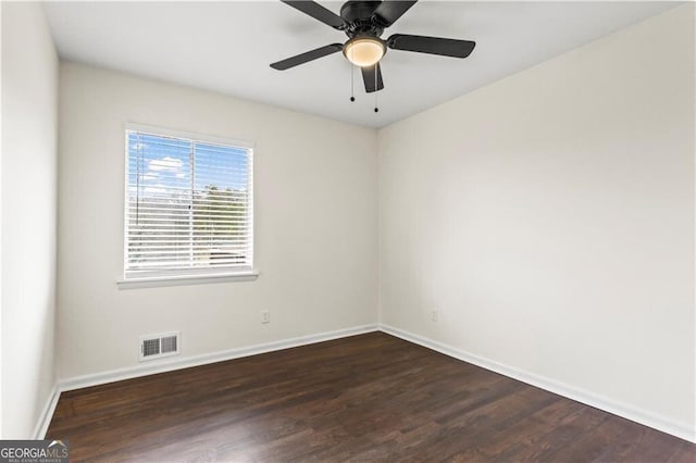 empty room featuring dark wood-type flooring, visible vents, ceiling fan, and baseboards