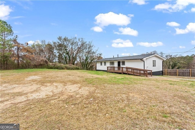 rear view of house with a yard, fence, and a wooden deck