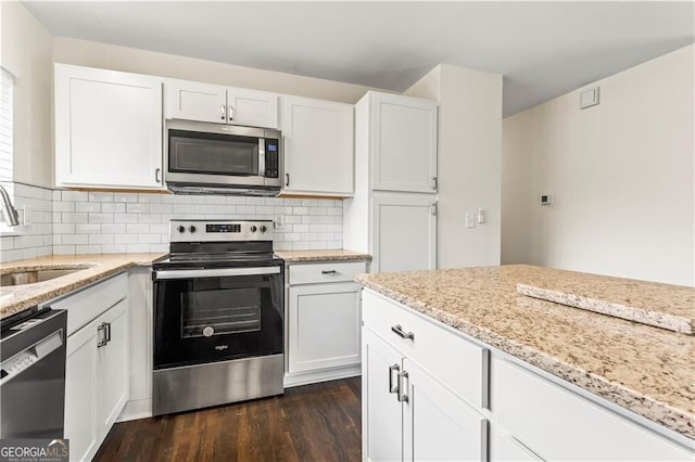 kitchen featuring stainless steel appliances, dark wood-style flooring, a sink, white cabinets, and tasteful backsplash