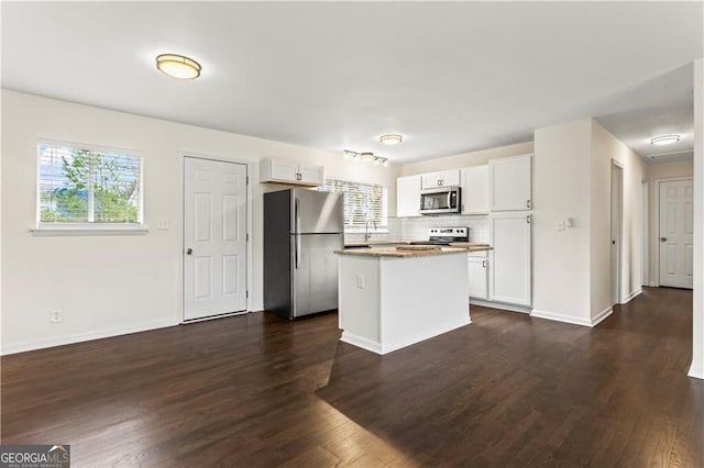 kitchen featuring decorative backsplash, dark wood-style floors, a center island, stainless steel appliances, and white cabinetry