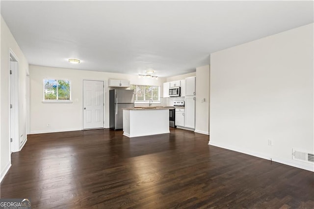 unfurnished living room featuring dark wood-type flooring, visible vents, a sink, and baseboards