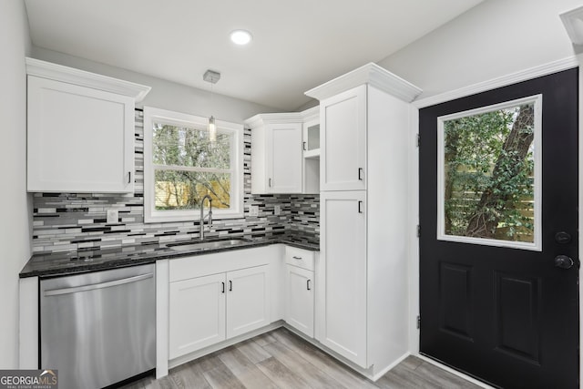 kitchen featuring light wood-style flooring, a sink, white cabinetry, stainless steel dishwasher, and backsplash