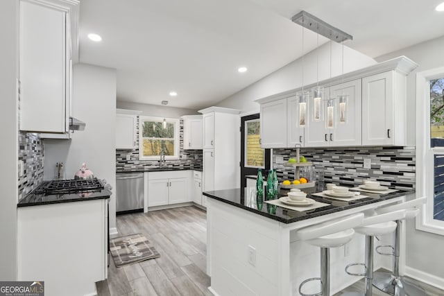 kitchen featuring a peninsula, stainless steel dishwasher, dark countertops, and a wealth of natural light