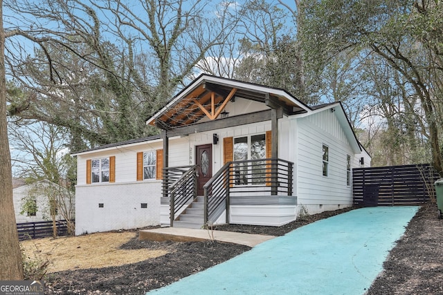 view of front of house with crawl space, fence, a porch, board and batten siding, and brick siding