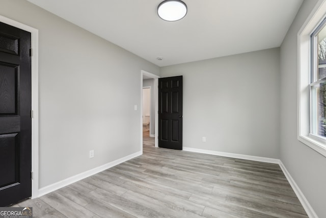 unfurnished room featuring a healthy amount of sunlight, baseboards, and wood finished floors