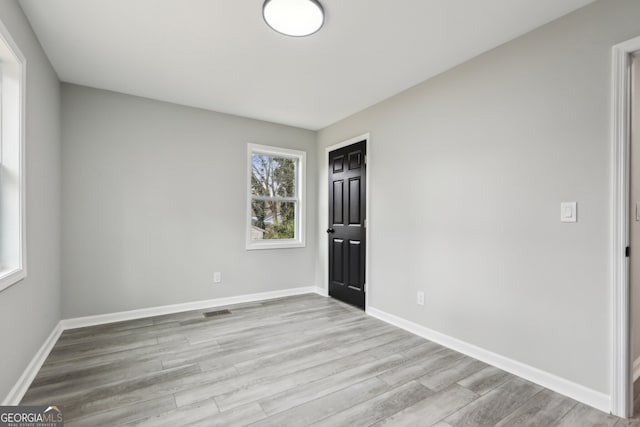 unfurnished room featuring visible vents, baseboards, and wood finished floors