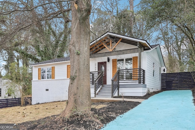 view of front of home featuring crawl space, fence, a porch, and brick siding