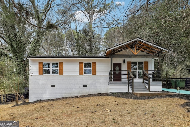 view of front of home featuring covered porch, brick siding, crawl space, and fence