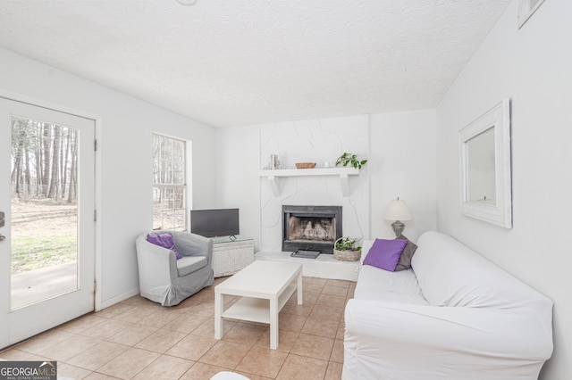 living room with a fireplace, a textured ceiling, and light tile patterned floors