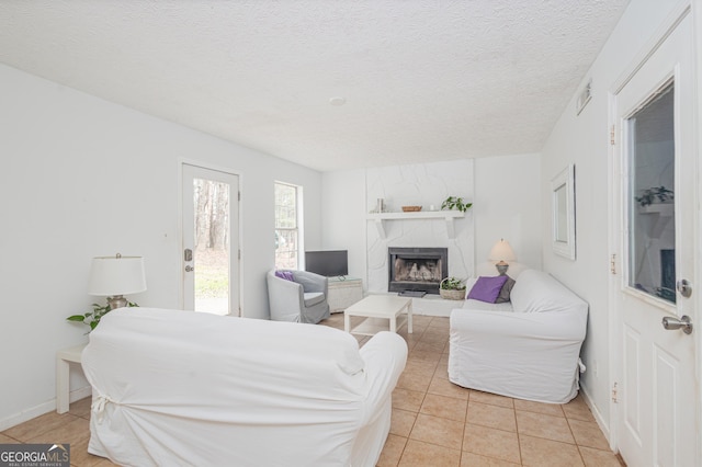 living area featuring light tile patterned floors, visible vents, a high end fireplace, a textured ceiling, and baseboards