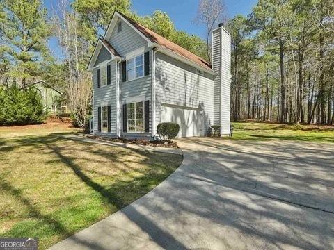 view of side of property featuring concrete driveway, a yard, and a chimney