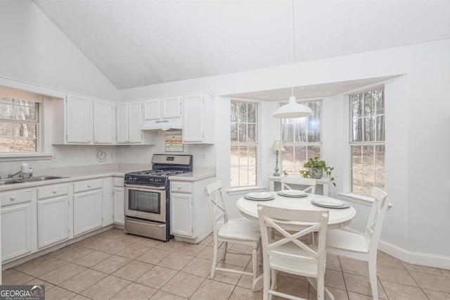 kitchen with light tile patterned floors, light countertops, under cabinet range hood, white cabinetry, and gas stove