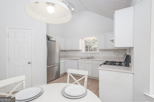 kitchen with light tile patterned floors, range with gas stovetop, freestanding refrigerator, white dishwasher, and a sink