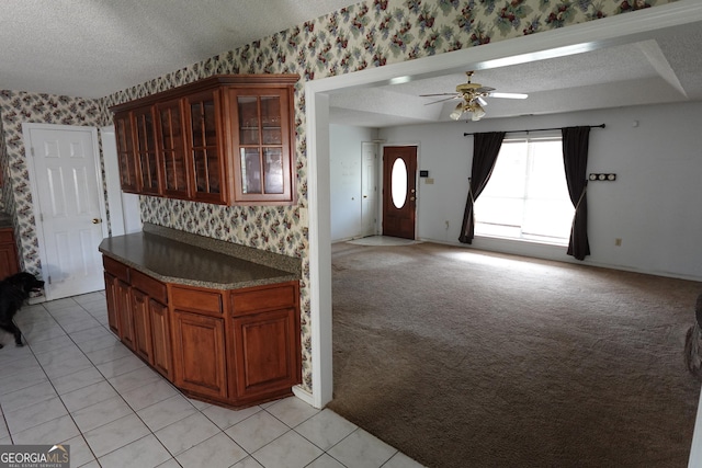 kitchen with glass insert cabinets, light colored carpet, a textured ceiling, and wallpapered walls